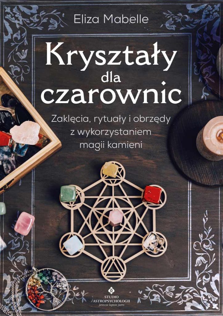 Okładka książki „Kryształy dla czarownic” Elizy Mabelle z kryształami ułożonymi na siatce kryształowej w formie świętej geometrii, zapaloną świecą rytualną, pudełkiem kamieni, wahadełkiem, amuletem z drzewem życia i roślinnymi ornamentami na ciemnym tle.
